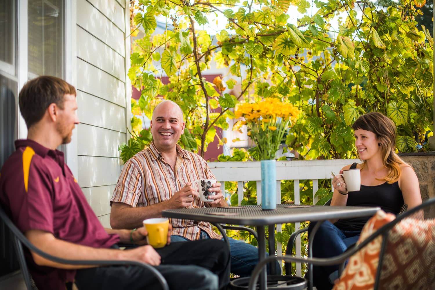 A group of friends have coffee together and chat on the porch of one of our transitional living homes in North Carolina